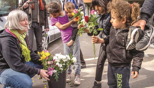 A woman from a local charitable association distributes flowers to children, including Kurdish migrants, outside a gymnasium in Grande-Synthe where they have taken refuge yesterday after a fire destroyed one of the biggest migrant camps in France on Monday.