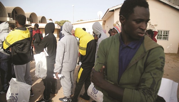 This picture taken earlier this month shows Gambian migrants who voluntarily returned from Libya queuing with plastic bags from the International Organisation for Migration (IOM) as they wait for registration at the airport in Banjul.