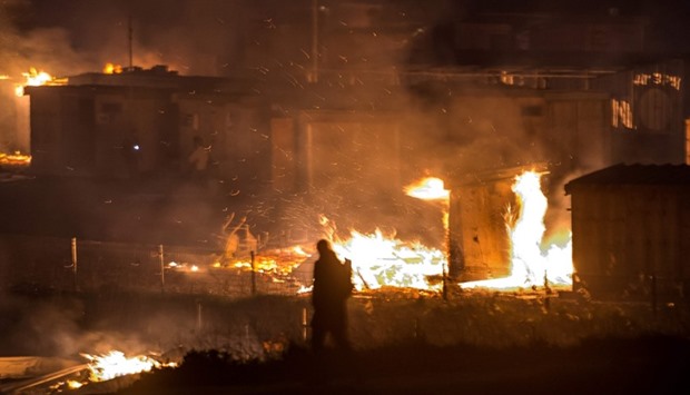 Migrants evacuate as a huge fire blazes through the Grande-Synthe migrant camp outside the northern French city of Dunkirk.