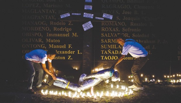 People lift a mock victim during a prayer vigil in support of the families of victims of extra-judicial killings in Manila yesterday.