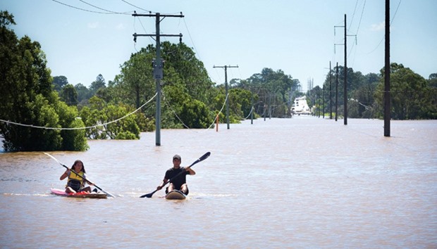 Kayakers paddle on the flooded Logan River, caused by Cyclone Debbie, as it flows over the Mt Lindesay Highway in Waterford West near Brisbane, Australia, yesterday.