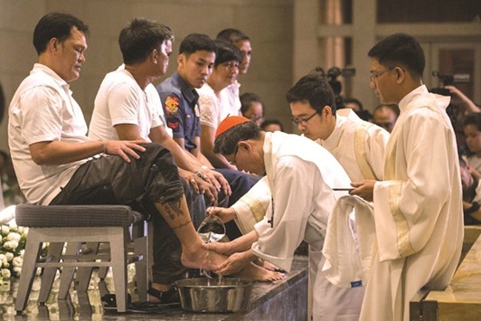 Manila Archbishop Luis Antonio Cardinal Tagle washes the feet of churchgoers during the evening mass at the Manila Cathedral yesterday.