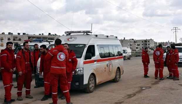 Syrian Red Crescent paramedics wait for buses evacuating civilians from government-held villages on a highway in eastern Aleppo, on Friday.
