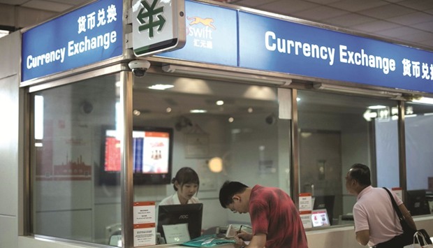 A man changes foreign currency into Chinese yuan at a currency exchange office at Hongqiao airport in Shanghai. The yuan waslittle changed at 6.8876 per dollar yesterday in Shanghai.
