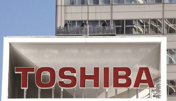 The Toshiba logo  is seen as window cleaners work on the companyu2019s headquarters in Tokyo. Right: The Apple logo is pictured inside an Apple store at a shopping district in Tokyo. Appleu2019s plan may improve Toshibau2019s prospects for emerging from a fiasco in its Westinghouse nuclear business that has led to billions of dollars in losses.