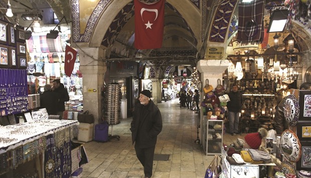 A pedestrian walks past retail stores in the Grand Bazaar in Istanbul. Cemil Ertem, an adviser to President Tayyip Erdogan, said he expected inflation in Turkey to fall rapidly from the second half of 2017, after annual inflation hit its highest in 8-1/2 years in March as chronic weakness in the lira currency stoked a surge in consumer prices.
