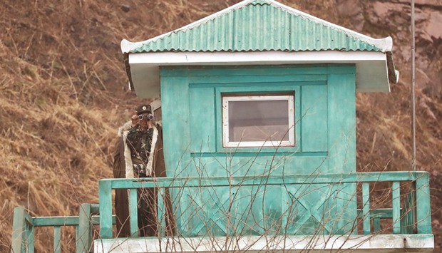 A North Korean soldier looks through a pair of binoculars at a watch tower in Sinuiju, North Korea, just across from Dandong of Chinau2019s Liaoning province yesterday.