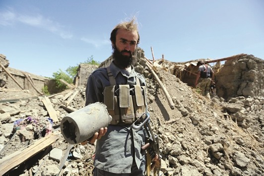 An Afghan policeman holds a part of a rocket as he inspects a house, which was damaged prior to the bombing, after an operation near the site of a US bombing in the Achin district of Nangarhar province in eastern Afghanistan yesterday.