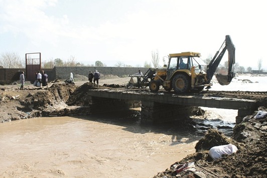Workers trying to repair a damaged bridge over a river after torrential rains overflowed rivers and flooded houses, in the northeastern Azarshahr city, south of Tabriz.
