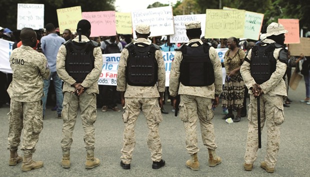 This February 17 picture shows Haitian police officers watching as protesters in Port-au-Prince demand that the MINUSTAH (UN Stabilisation Mission in Haiti) pay for the cholera outbreak in 2010.