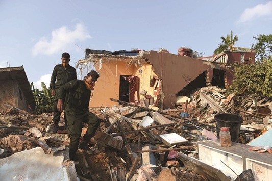 Military personnel walk among damaged homes at the site of a collapsed garbage dump in Colombo yesterday.