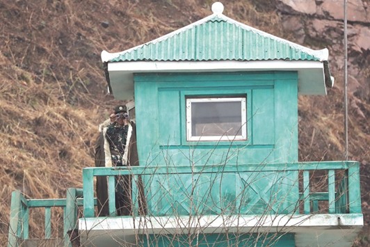 A North Korean soldier looks through a pair of binoculars at a watch tower in Sinuiju, North Korea.
