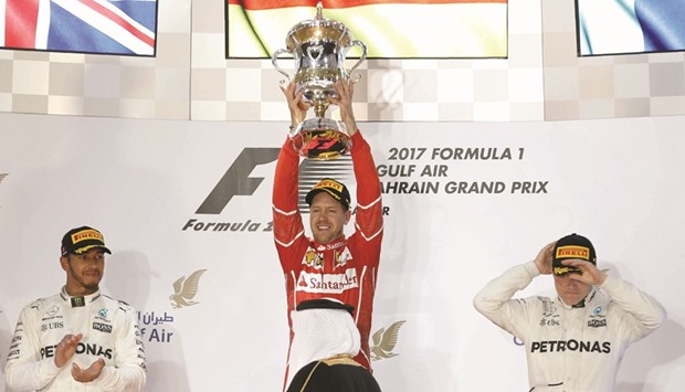 Ferrari driver Sebastian Vettel of Germany (C) holds the winneru2019s trophy on the podium flanked by second-placed Mercedes driver Lewis Hamilton of Britain and third-placed Mercedes driver Valtteri Bottas of Finland.