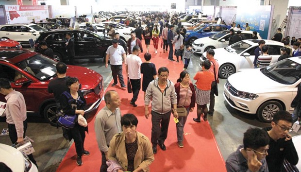 People walk through an auto exhibition in Nanjing, in Chinau2019s Jiangsu province. Manufacturers have reaped a windfall as the fast-expanding Chinese middle class hits the road, but clouds loom as Volkswagen, Toyota, GM, and other top nameplates pitch their latest models starting on Wednesday at Chinau2019s biggest auto showcase.
