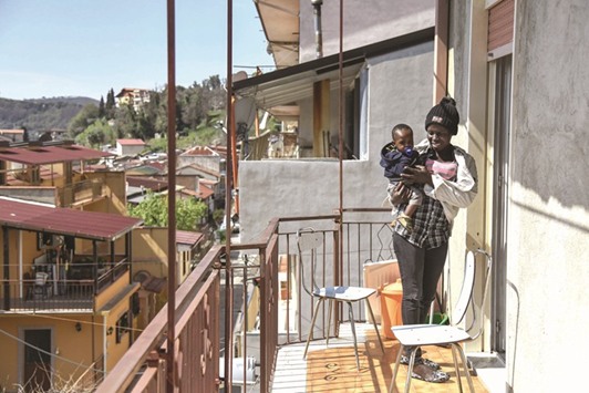 Hawa and her son Lamin, migrants from Gambia, stand at a balcony in Santu2019Alessio in Aspromonte, a small village of 330 inhabitants in Calabria, southern Italy.