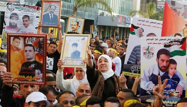 Palestinians hold pictures of relatives held in Israeli jails during a rally marking Palestinian Prisoner Day in the West Bank city of Nablus