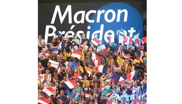 Supporters of the presidential election candidate for the En Marche ! movement Emmanuel Macron wave flags during a campaign meeting yesterday at the Bercy Arena in Paris. Macron planned his biggest rally yet at the Bercy sports and concert hall, a venue with a capacity of 20,000.