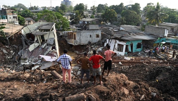 Sri Lankan residents survey damaged homes at the site of a collapsed garbage dump in Colombo