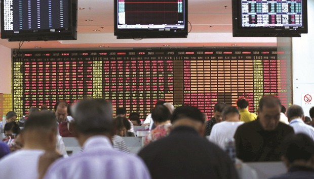 Investors look at computer screens in front of an electronic board showing stock information at a brokerage house in Shanghai. The Composite of Shanghai closed down 0.7% to 3,222.17 points yesterday.