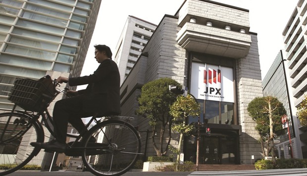 A man cycles past the Tokyo Stock Exchange. Japanese stocks have been battered so badly that theyu2019re too cheap to ignore, says the $161bn investor Pictet Asset Management, after the Topix index tumbled to its fifth straight weekly loss.