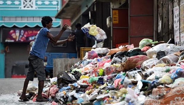 A Sri Lankan man throws garbage onto a rubbish pile on a street in Colombo on Tuesday.