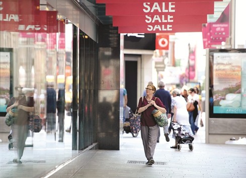 A pedestrian walks underneath signs promoting a sale in Dublin. In its latest World Economic Outlook report, the IMF said growth this year in the 19-nation eurozone would be 1.7%, up 0.1 percentage point from its January estimate but unchanged from the 2016 performance.