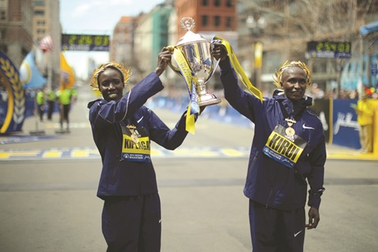 Kenyau2019s Edna Kiplagat (left) and compatriot Geoffrey Kirui lift the trophy after they won the womenu2019s and menu2019s divisions of the Boston Marathon respectively on Monday. (Reuters)