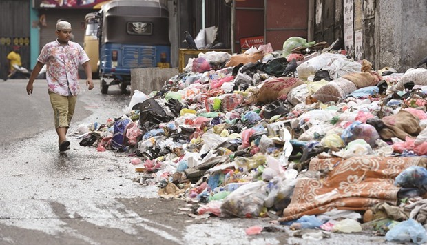 A boy walks by piles of garbage on a street in Colombo yesterday.