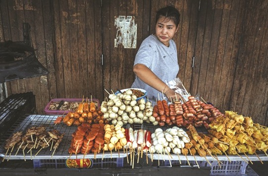 A woman arranges fried snacks on her street food cart the Pratunam district of Bangkok.