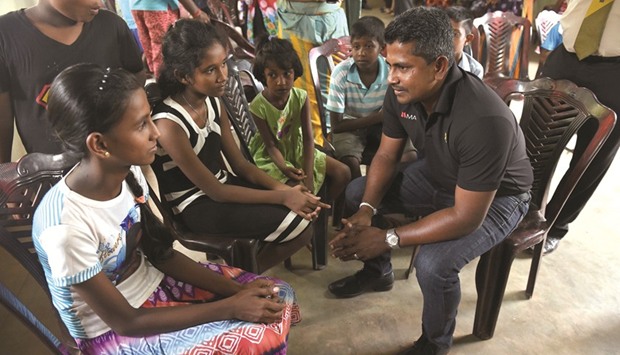 Cricketer Rangana Herath, right, meets with survivors and displaced people at a relief camp after a massive garbage mountain collapse in the Meethotamulla suburb of Colombo yesterday.
