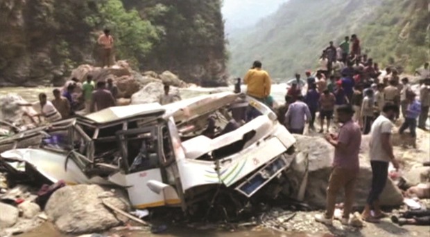 People and police gather at the site where a bus fell off a mountain road in Shimla yesterday.