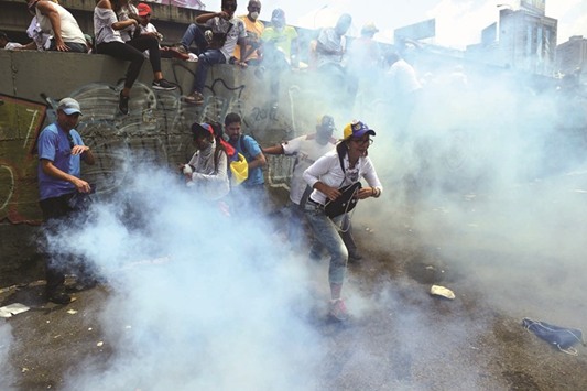 Demonstrators run away from tear gas canisters thrown by the police during a rally against Venezuelan President Nicolas Maduro, in Caracas on Wednesday.