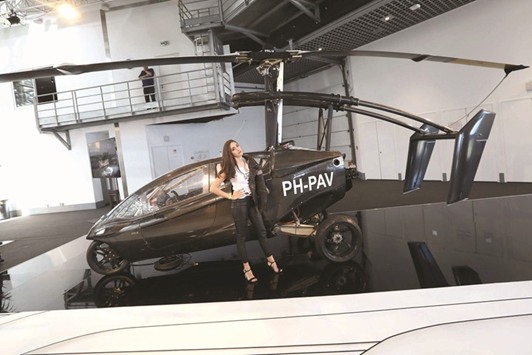 A woman poses near the u2018Pal-V Libertyu2019 flying car, a gyrocopter with three wheels and a retractable rotor, on display as part of the u2018Top Marquesu2019 show, dedicated to exclusive luxury goods, yesterday in Monaco.