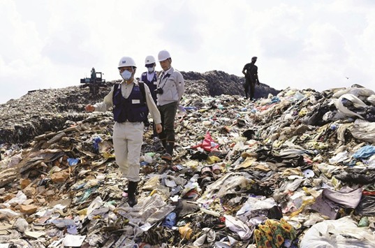 Japanese officials with a disaster relief team survey the site of a garbage dump collapse that killed 32 people on the northeastern edge of Colombo yesterday.