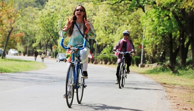 A woman flashes victory signs as she rides a bicycle during Girls on Bike rally in Islamabad on Sunday.