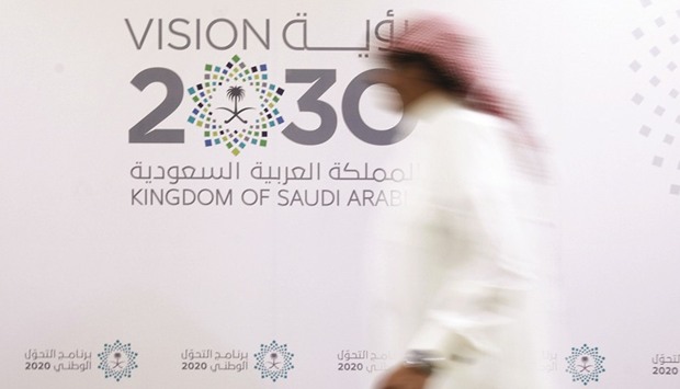 A Saudi man walks past the logo of Vision 2030 in Jeddah. The kingdom has embarked on what it describes as an unprecedented shakeup of an economy thatu2019s heavily reliant on oil.