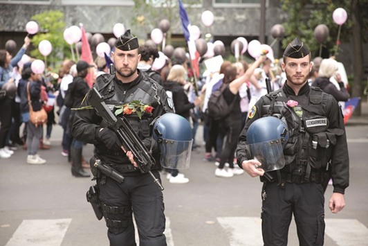Police officers bearing flowers stand guard during a rally organised by theu2018Angry Policemenu2019s Wivesu2019 (FFOC) in support of French officers, near the esplanade of the Champs de Mars, in Paris yesterday, two days after a gunman opened fire on police on the Champs Elysee avenue, killing an officer and wounding two others in an attack claimed by the Islamic State group.