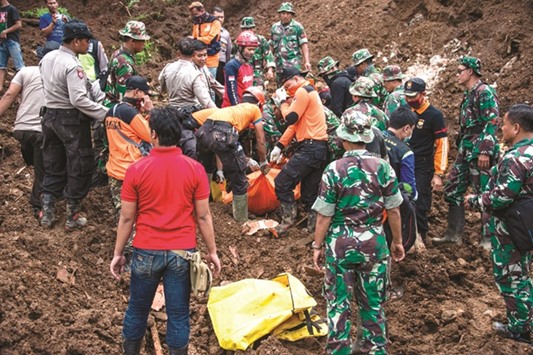 Rescuers recover the body of a woman from the scene after a wall of mud slammed onto houses from a hillside following heavy rainfall in Ponorogo district, East Java.