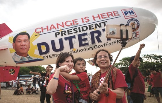 Supporters of  President Rodrigo Duterte pose in front of a blimp for a picture during a protest calling for the ouster of Vice President Leni Robredo over his drug war criticism, in Manila, yesterday.