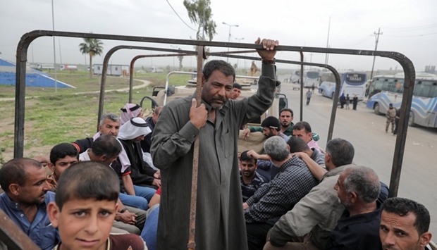 Displaced Iraqi men wait in a truck to be transported to a camp as the battle between the Iraqi Counter Terrorism Service and Islamic State militants continues nearby, in western Mosul, Iraq.