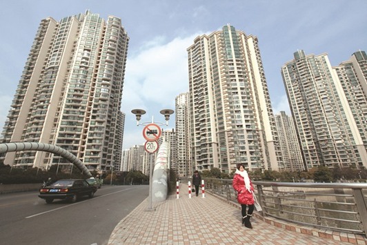 A woman walks in front of a housing complex in Shanghai. The worldu2019s hottest property stocks are to be found in China as tougher measures to cool real estate prices fail to deter investors.