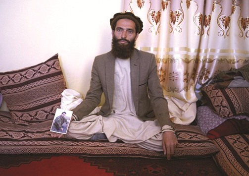 Afghan resident Ahmadullah poses for a photograph with a picture of his brother Shir Mohamed, an Afghan National Army (ANA) soldier who was killed in a Taliban attack on an army base, at his house on the outskirts of Mazar-i- Sharif.