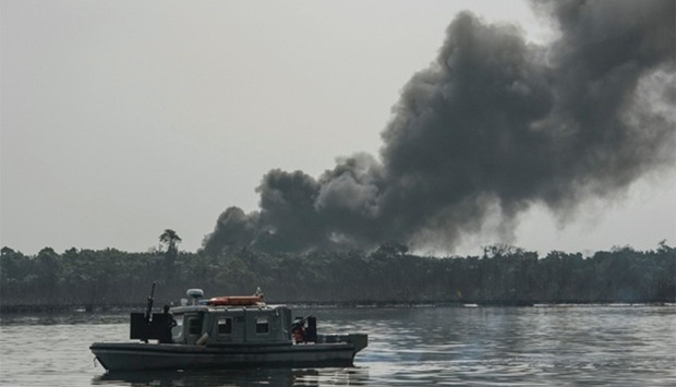 A cloud of smoke rises from an illegal oil refinery  in the Niger Delta region
