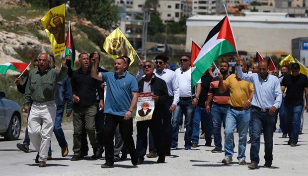 Palestinian protesters wave their national flag and portraits of prominent prisoner and popular leader Marwan Barghouti, during a demonstration in solidarity with Palestinian prisoners on hunger strike in Israeli jails, in front of the Israeli-run Ofer prison in the West Bank village of Betunia on April 20, 2017.
