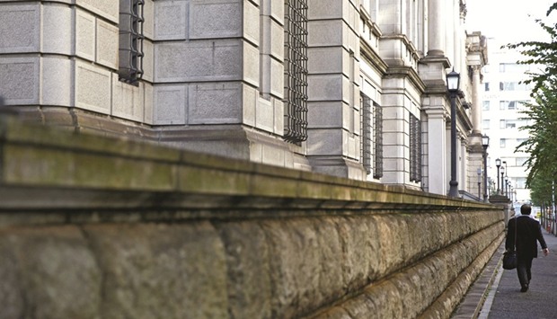 A man walks past the Bank of Japan building in Tokyo. With the economy in good shape, the BoJ is widely expected to leave unchanged its commitment to guide short-term interest rates at minus 0.1% and the 10-year government bond yield around 0% through aggressive asset purchases.