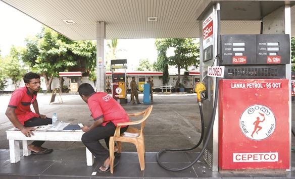 Workers rest next to a closed fuel filling point during an island-wide Ceypetco (Ceylon Petrolium Corporation) strike at a fuel station in Colombo yesterday.