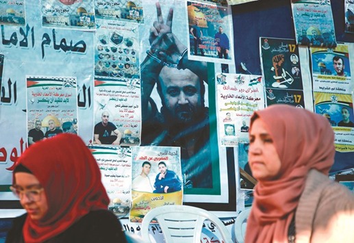 A Palestinian woman walks past a wall bearing posters including a portrait of leader and prominent prisoner Marwan Barghouti, during a rally in the West Bank city of Ramallah in support of him and other prisoners on hunger strike in jails yesterday.