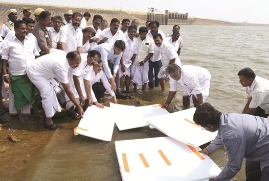 Tamil Nadu Co-operatives Minister Sellur K Raju (centre), government officials and civic workers use thermocol polystyrene sheets to attempt to cover the reservoir at the Vaigai Dam in Madurai.