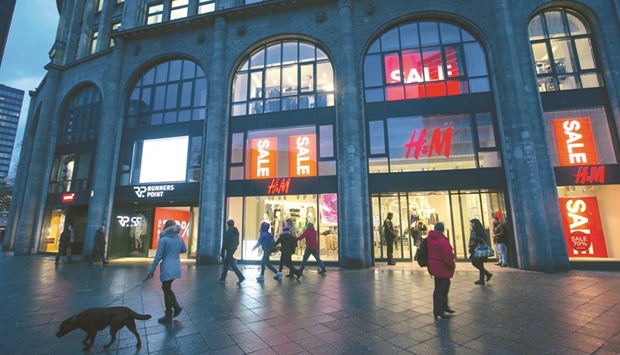 Pedestrians pass a clothing fashion store as sales promotion signs are seen on display in Berlin. u201cThe German economy is growing strongly,u201d Ifo chief Clemens Fuest said in a statement.