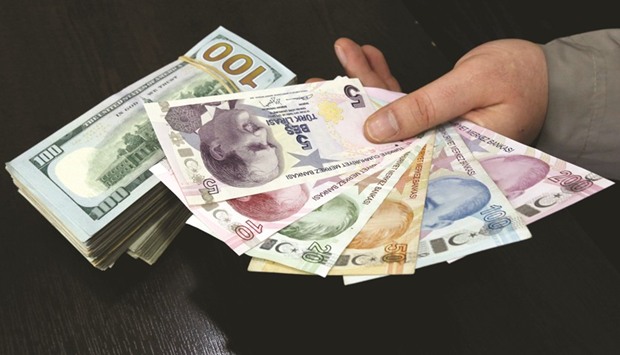 A money changer holds Turkish lira banknotes next to US dollar bills at a currency exchange office in central Istanbul. Since Turks keep about 40% of their 1.48tn liras ($411bn) of deposits in currencies like the dollar and euro, what they do with those savings can have a meaningful impact on the currencyu2019s trajectory.